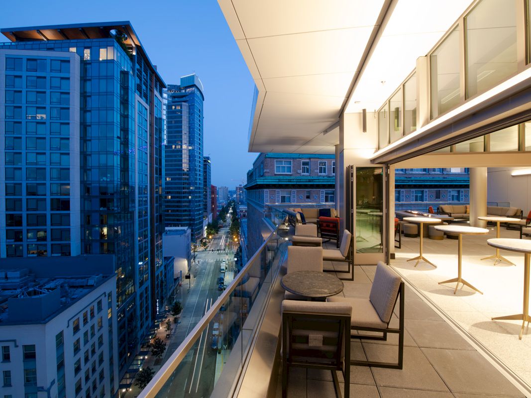 View of a modern office rooftop terrace with seating overlooking downtown skyscrapers.
